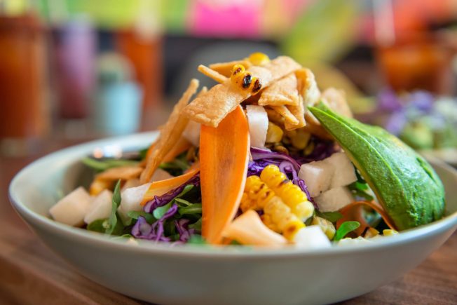 Mexican salad with arugula, avocado, charred corn, jicima, carrots, and tortilla strips