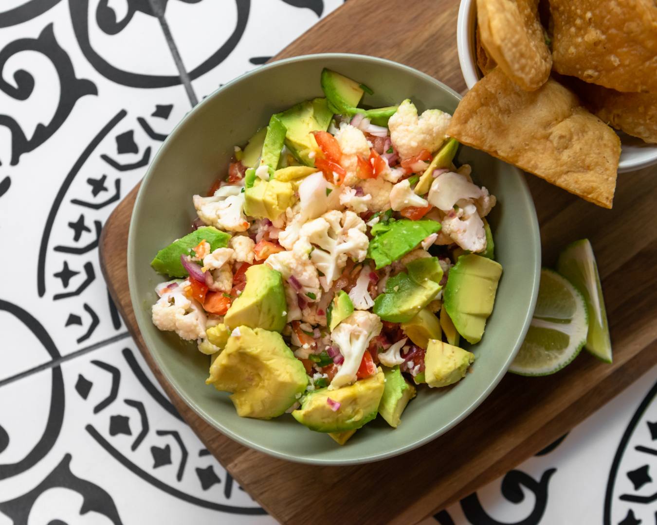 Cauliflower ceviche with tortilla chips and cut limes on wooden cutting board