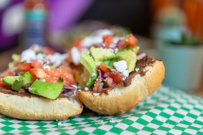 Avocado, tomato, red onions, vegan cheese, and beans on a roll